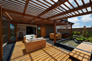 Wooden pergola covering patio with outdoor furniture. 